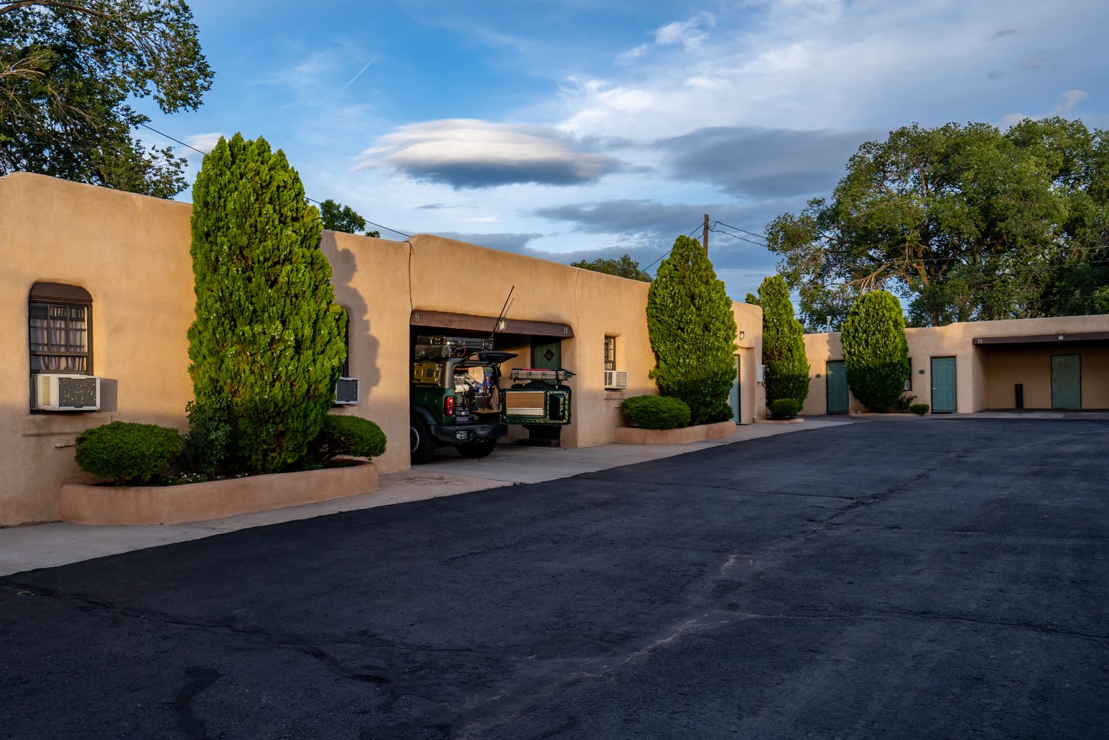 Adobe rooms and covered carports curving around the quiet U-shaped motor court at golden hour