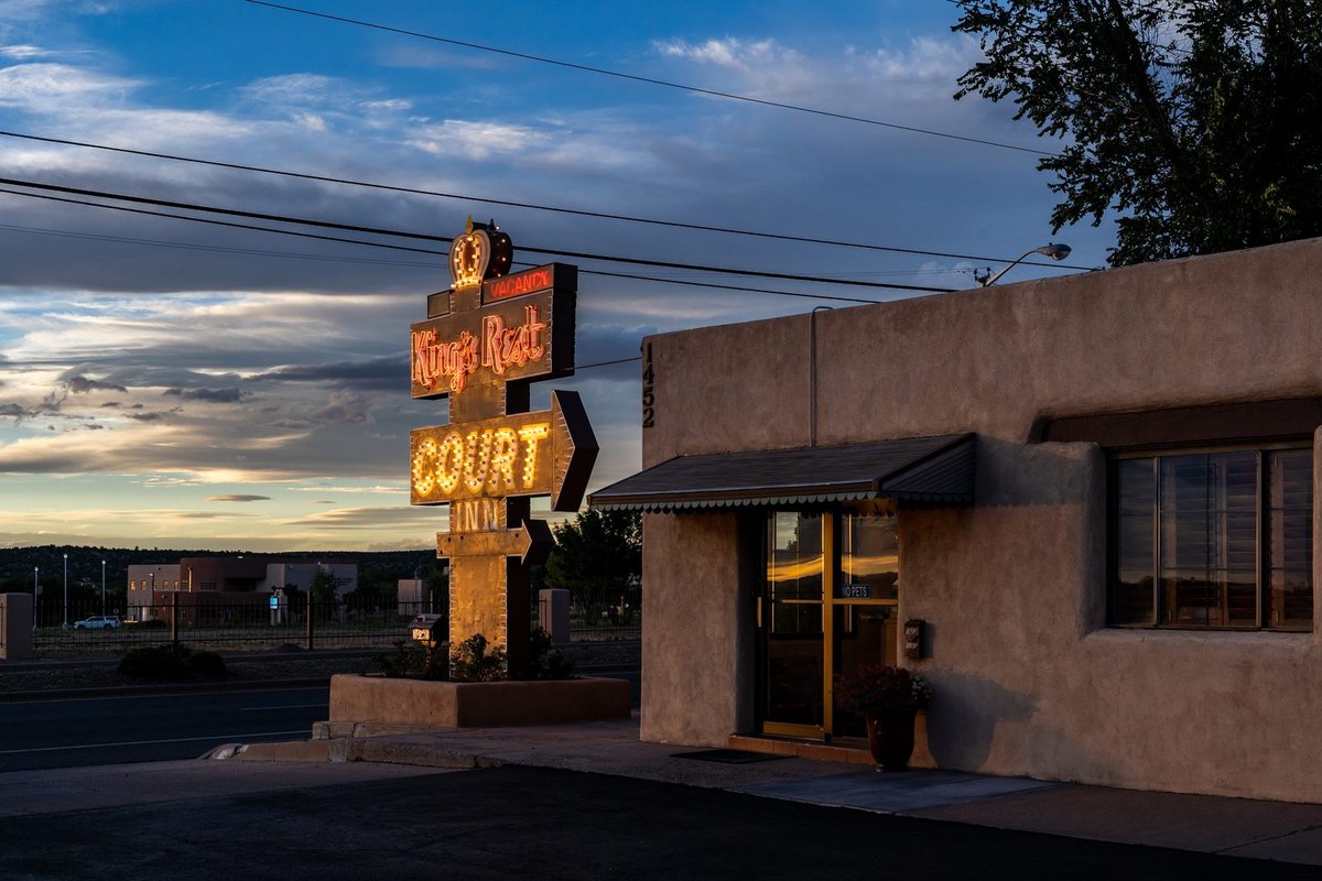 King's Rest Court neon sign glowing at dusk beside the adobe office on Cerrillos Road