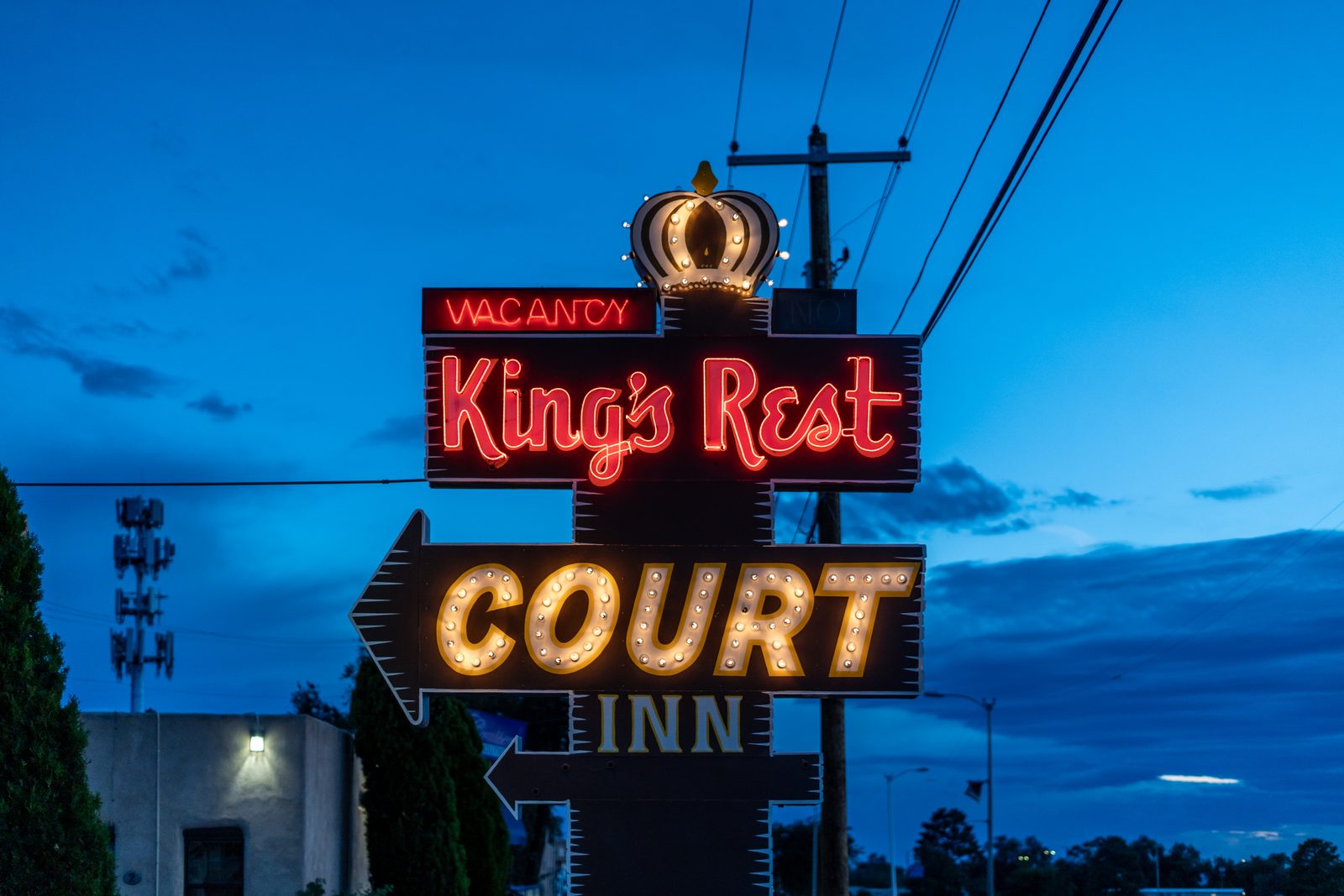 Vintage King's Rest Court Inn neon sign with crown and VACANCY lit against a blue evening sky